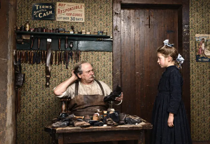 Bottega di calzoleria con artigiano e cliente, colorizzazione da fotografia d’archivio circa 1903 — originale Library of Congress.